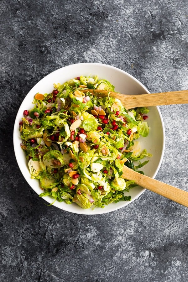 overhead shot of brussel sprouts salad in white serving bowl with tongs