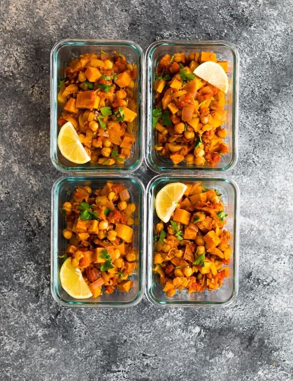Overhead shot of four glass meal prep containers filled with vegan moroccan chickpea skillet
