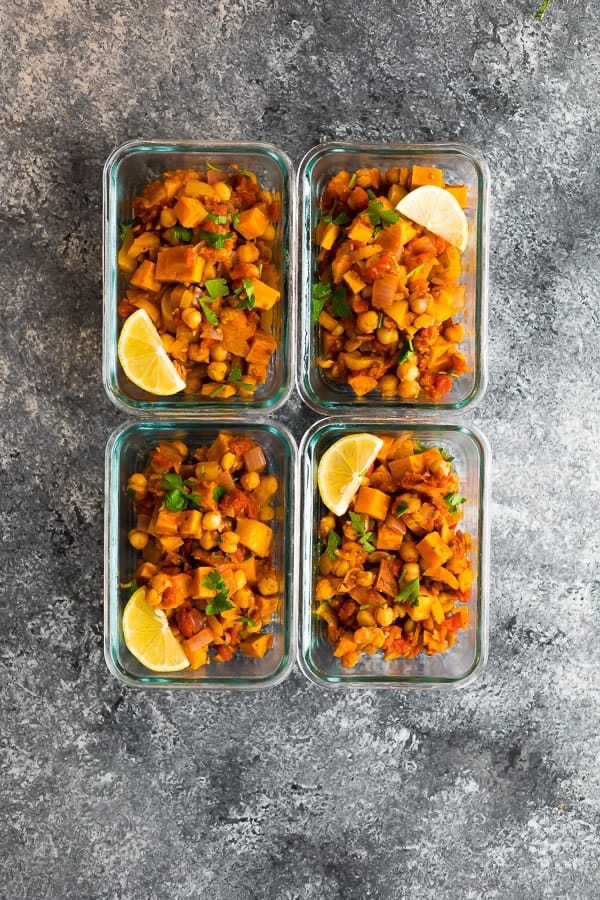 Overhead shot of four glass meal prep containers filled with vegan moroccan chickpea skillet