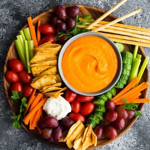 overhead shot of roasted red pepper hummus and chopped vegetables in a large bowl