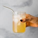 hand holding glass mason jar with apple cider vinegar drink
