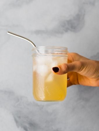 hand holding glass mason jar with apple cider vinegar drink
