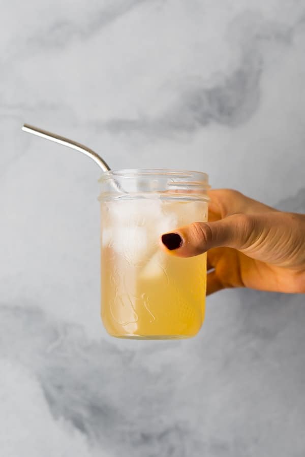 hand holding apple cider vinegar drink in mason jar