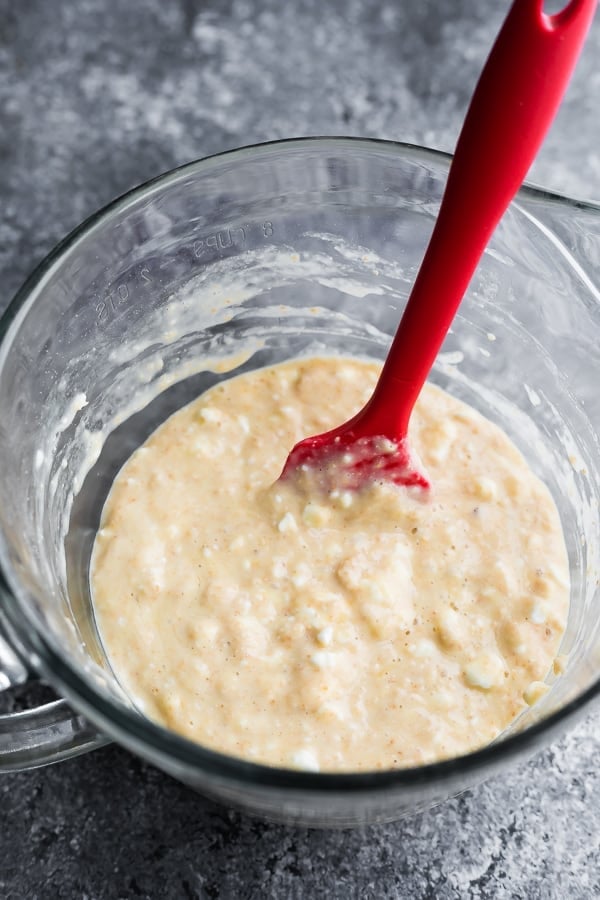 wet ingredients for pancakes in large glass mixing bowl with red spatula 
