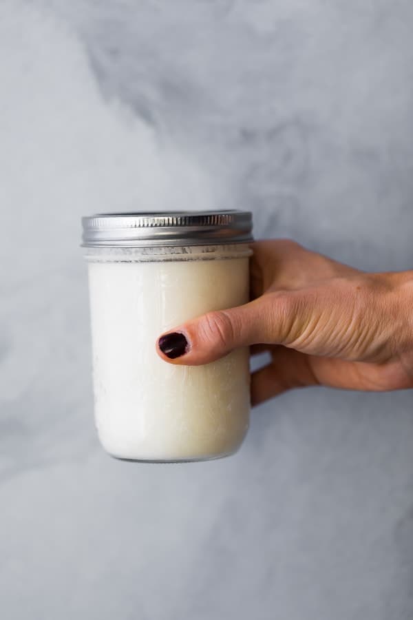 how to make buttermilk- hand holding mason jar with homemade buttermilk