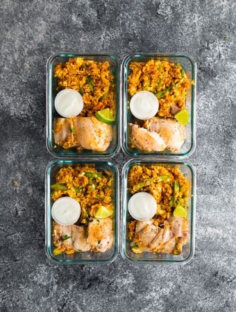 overhead shot of four glass meal prep containers with indian chicken