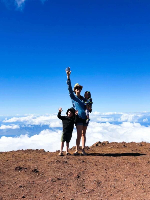 Denise standing with her two kids on top of a mountain