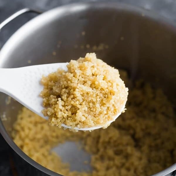 spoon scooping up quinoa over a large pot
