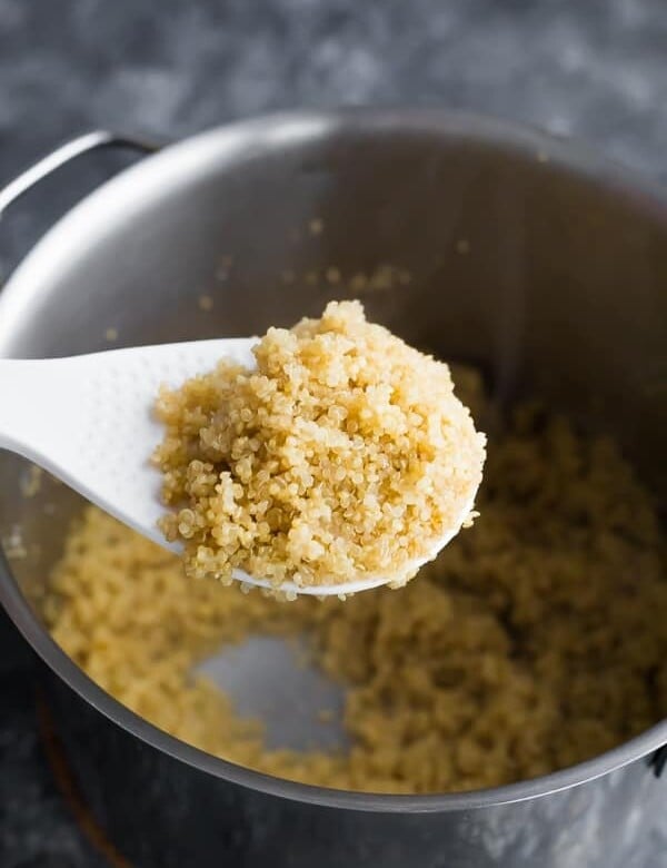 spoon scooping up quinoa over a large pot