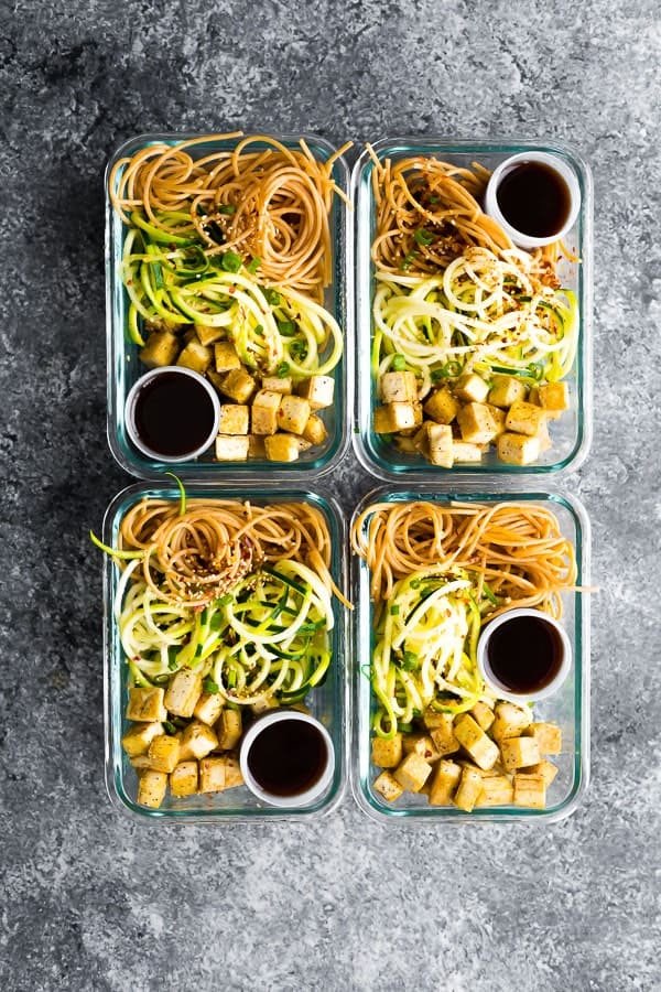 overhead shot of four spicy tofu noodle meal prep bowls in glass containers