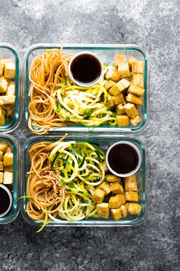 overhead shot of two glass meal prep containers filled with spicy tofu noodles