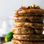 stack of zucchini chocolate chip pancakes with maple syrup being drizzled on top