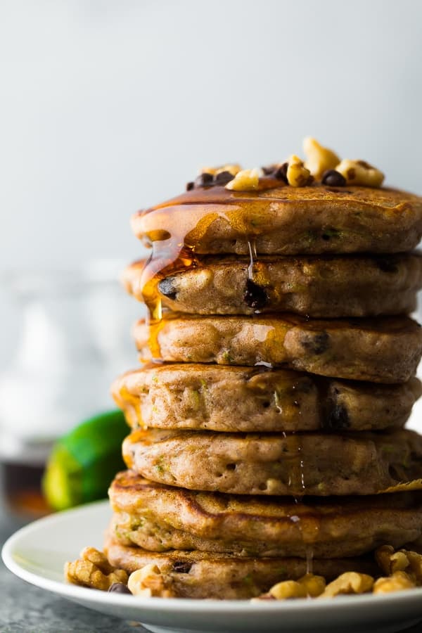 a stack of chocolate chip pancakes with syrup running down the side