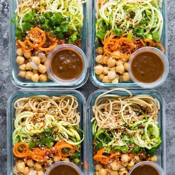 overhead shot of four glass containers with sesame noodle meal prep bowls