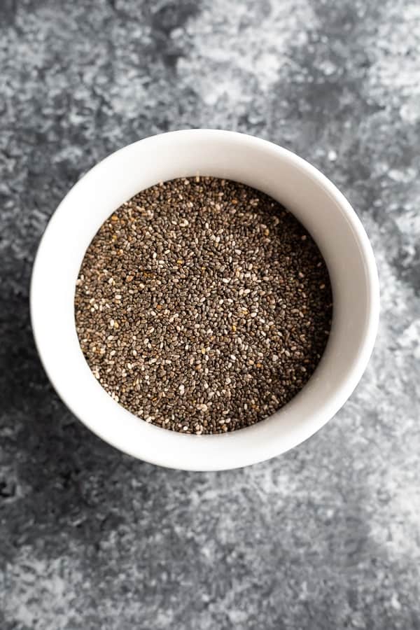 chia seeds in white dish, on grey backdrop, overhead view