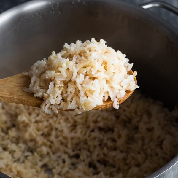 wooden spoon taking brown rice out of pot