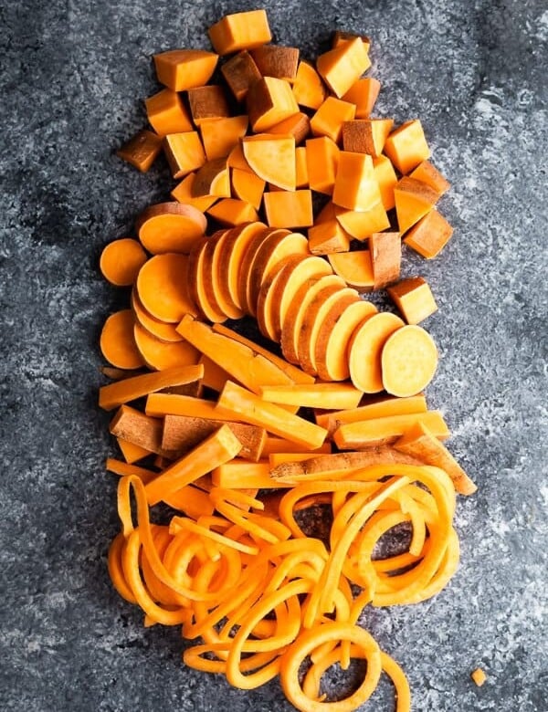 overhead shot of sweet potatoes cut in multiple ways on gray background