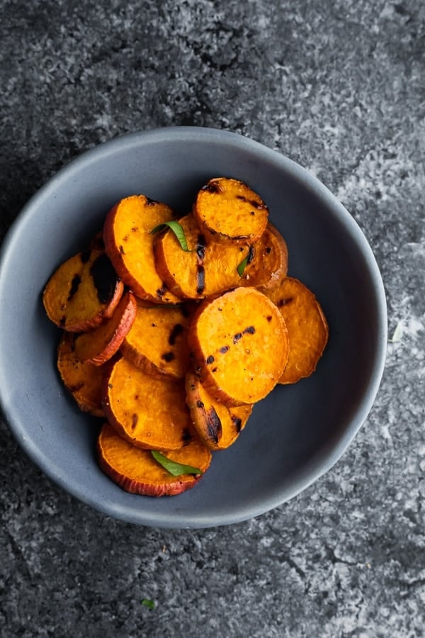 how long to cook sweet potatoes depends on the size and method; showing blue bowl of grilled sweet potatoes