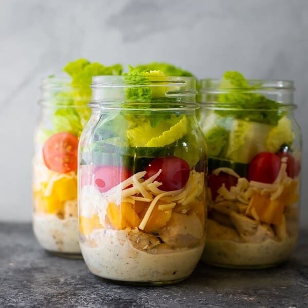 three glass mason jars filled with ranch chicken jar salads