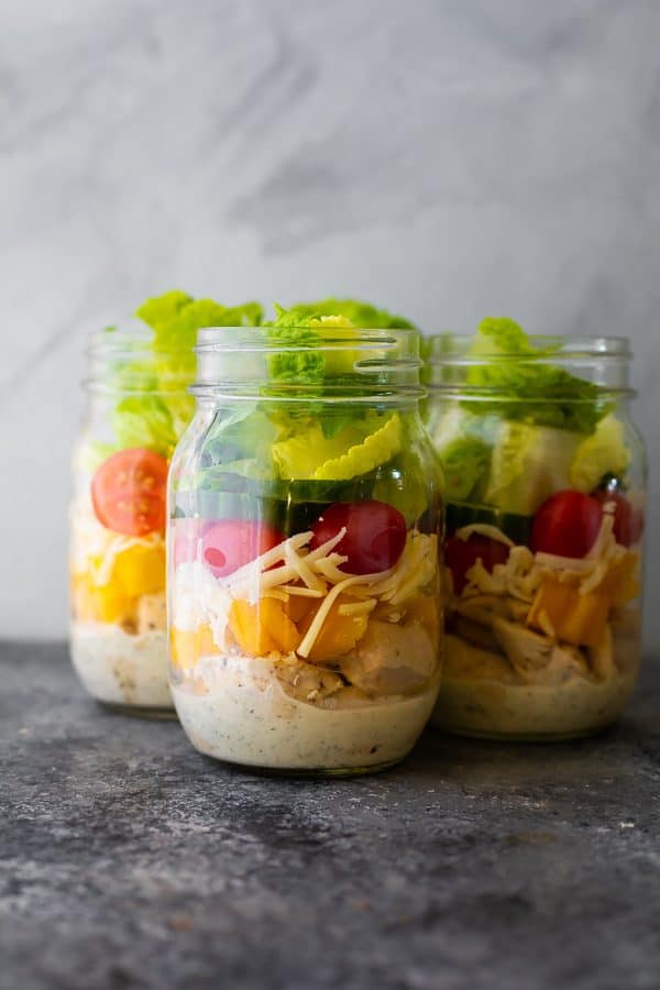 three glass mason jars filled with ranch chicken jar salads