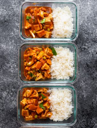 overhead shot of three glass meal prep containers filled with vegan slow cooker tikka masala