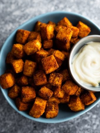 A blue bowl filled with crispy air fryer tofu and dipping sauce