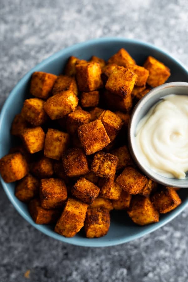 A blue bowl filled with crispy air fryer tofu and dipping sauce