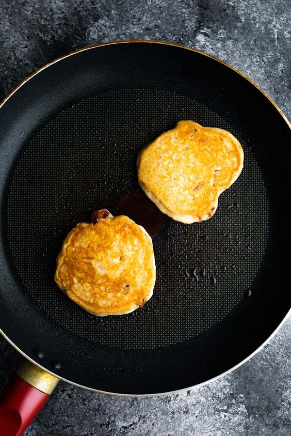 two homemade pancakes cooking in frying pan