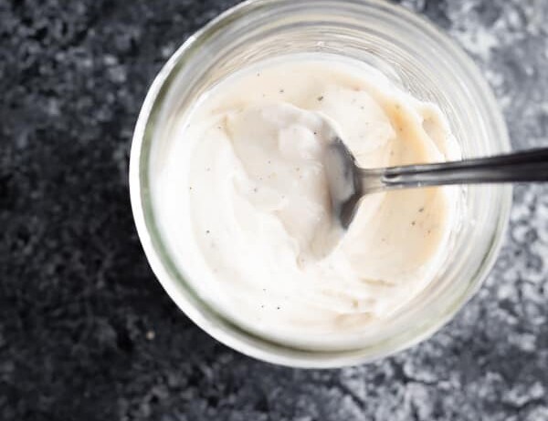 overhead shot of healthier caesar dressing in a mason jar with a spoon