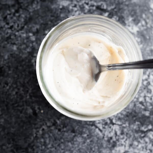 overhead shot of healthier caesar dressing in a mason jar with a spoon