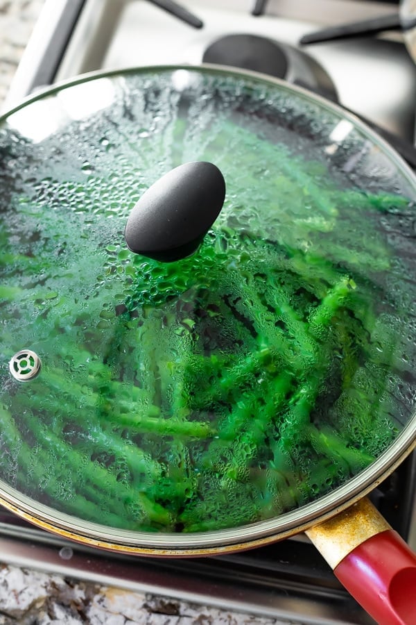 showing sauteed green beans with garlic cooking in pan with lid