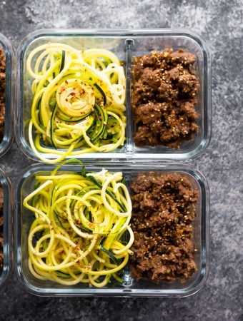 overhead shot of glass meal prep containers filled with sesame ginger beef and zucchini noodles