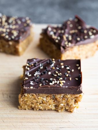 three pieces of chocolate tahini oat bars on wood board