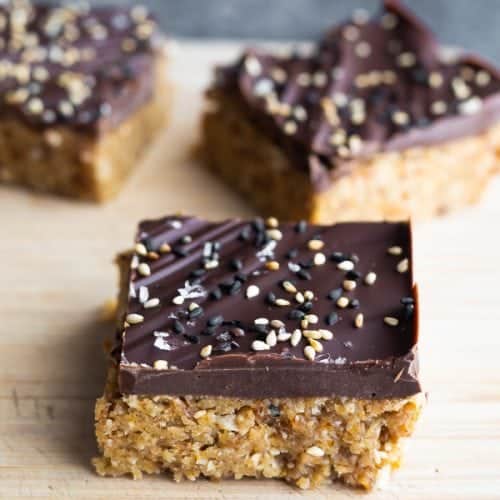 three pieces of chocolate tahini oat bars on wood board