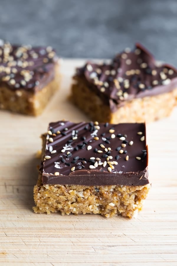 three pieces of chocolate tahini oat bars on wood board