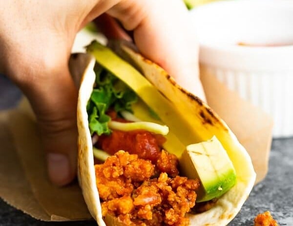 Close up of a hand holding a tofu taco