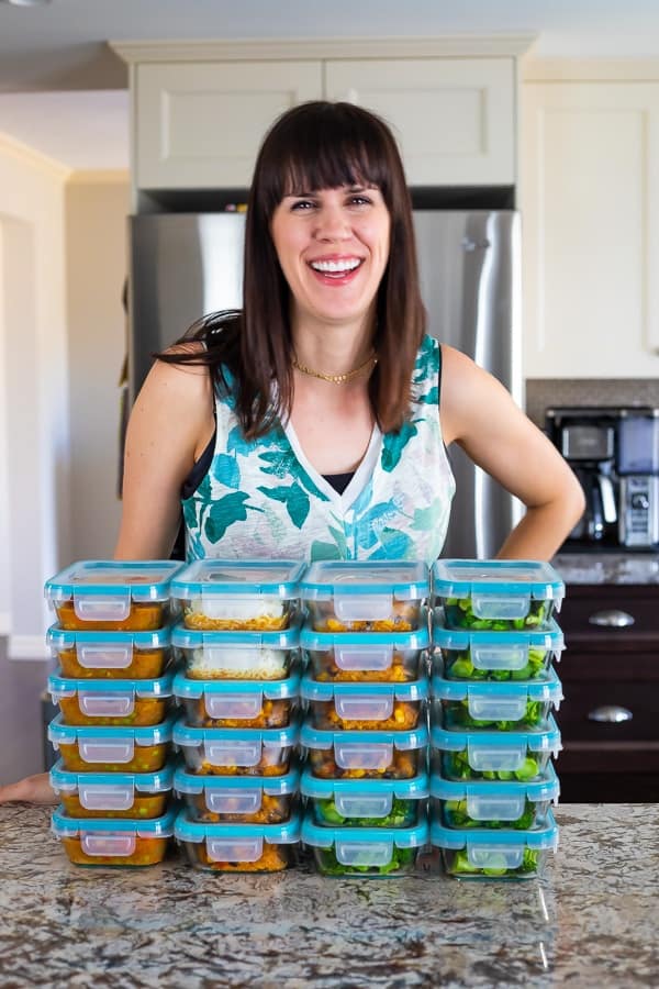 Denise standing behind a stack of glass meal prep containers filled with food