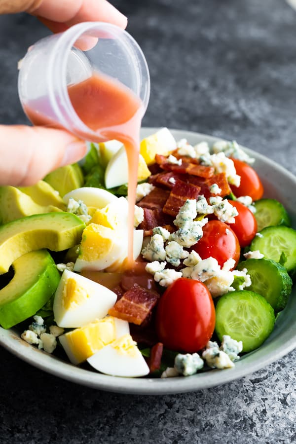 what is a cobb salad- showing dressing being poured over cobb salad