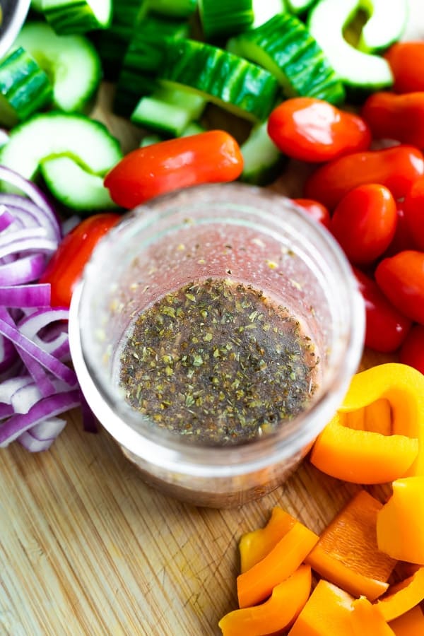 greek dressing recipe in jar surrounded by veggies