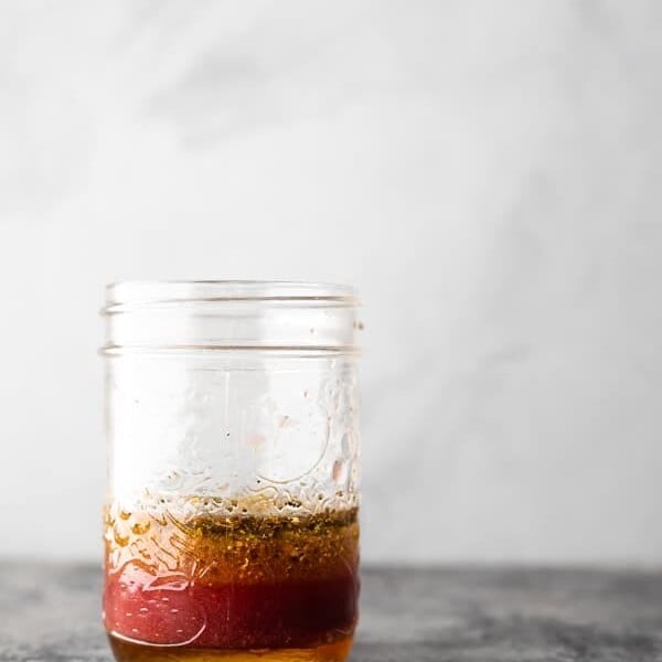 A glass mason jar filled with Greek salad dressing