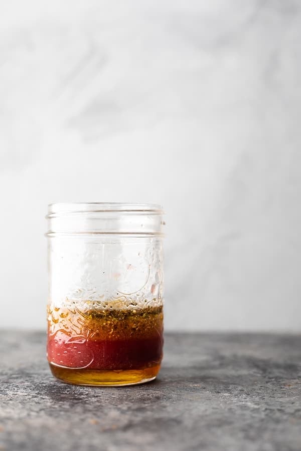 A glass mason jar filled with Greek salad dressing