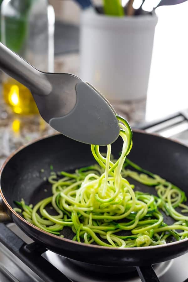 showing how to make zucchini noodles; tongs lifting noodles from pan
