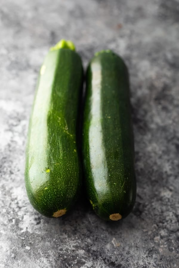 two medium sized zucchinis side by side from overhead on grey countertop
