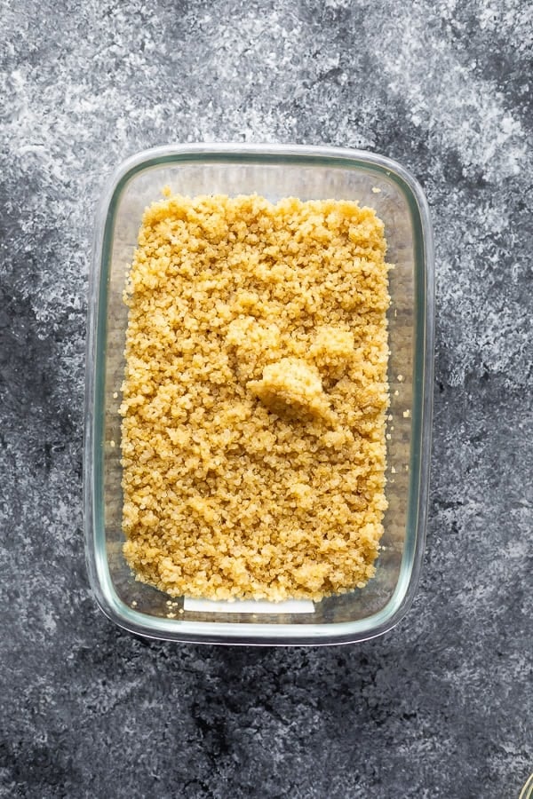 overhead shot of quinoa in glass meal prep container on gray background