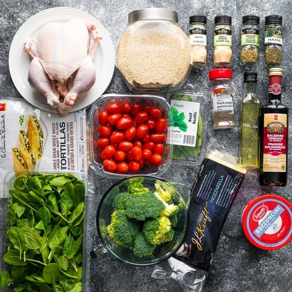 overhead shot of a variety of ingredients for whole chicken meal prep on gray background