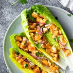 overhead shot of three barbecue chicken lettuce wraps on a gray plate