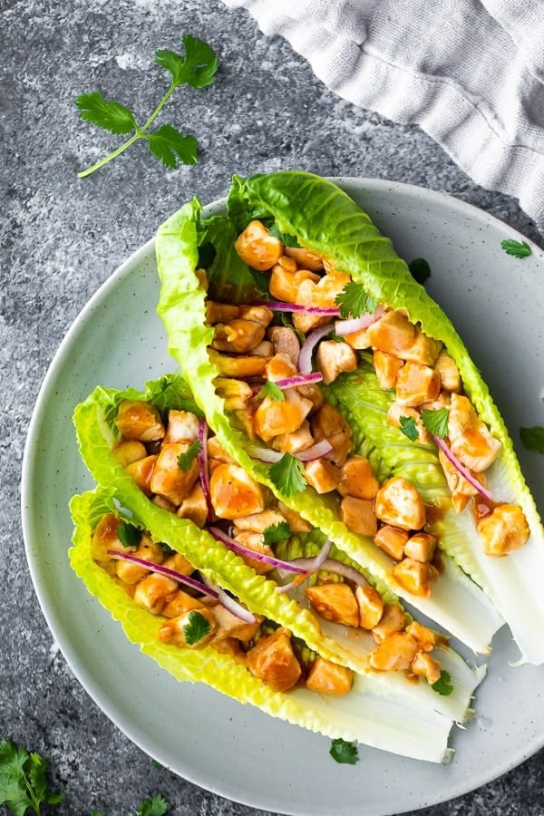 overhead shot of three barbecue chicken lettuce wraps on a gray plate