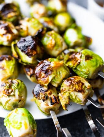 plate with grilled pile of brussels sprouts with garlic butter on skewers