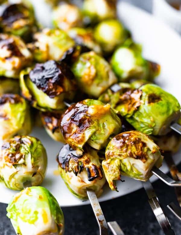 plate with grilled pile of brussels sprouts with garlic butter on skewers