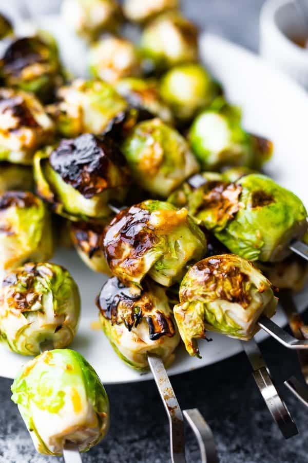 plate with grilled pile of brussels sprouts with garlic butter on skewers
